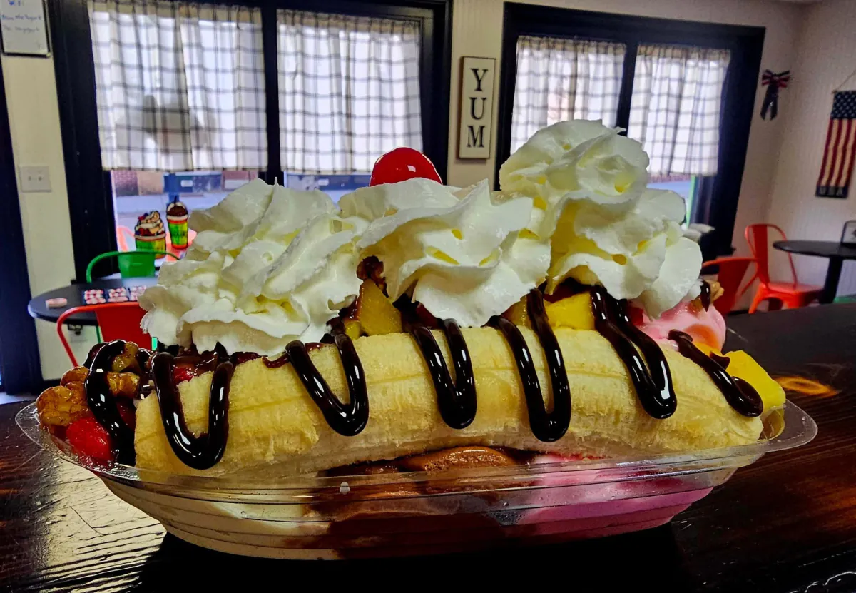 A loaded banana split with yogurt, fruit, whipped cream, and chocolate drizzle